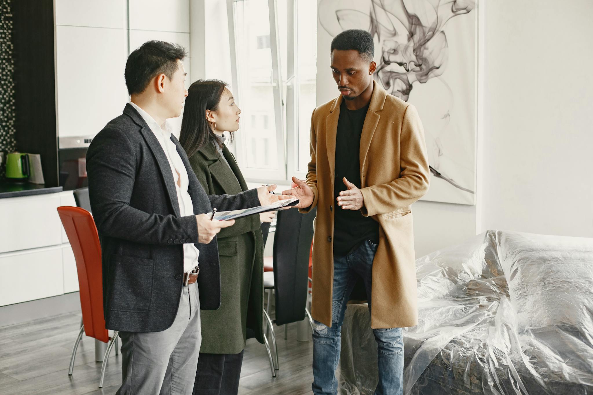 Three professionals engage in a conversation inside a contemporary office, promoting teamwork.
